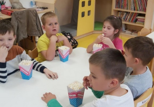 Dzieci jedzą popcorn